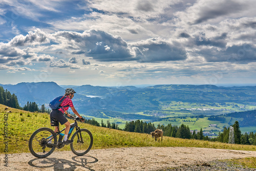 nice active senior woman riding her electric mountain bike at Mount Gruenten in the Allgaeu Alps , Bavaria, Germany