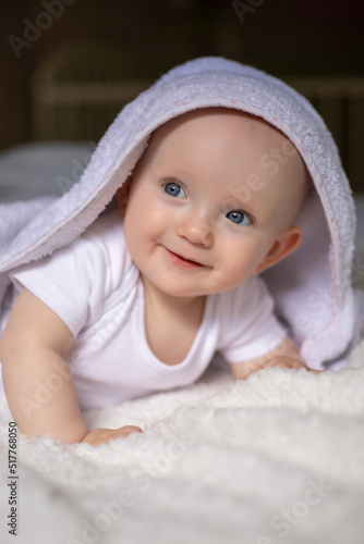 smiling baby looking at camera under a white blanket, towel. selective focus