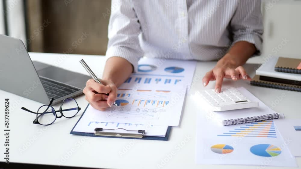 Close-up hands of business people working in office with laptop, paperwork and calculator on table Close-up hands of business people working in office with laptop, paperwork and calculator on table