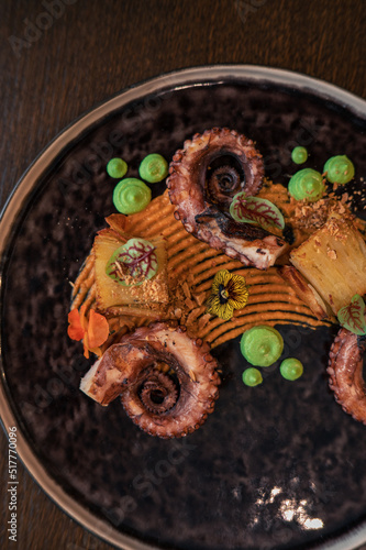 Octopus with potatoes on pea mash decorated with edible flowers