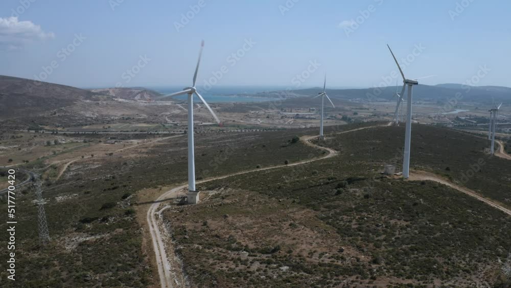 Wind turbines with moving rotating blades in wind energy field with bright blue sky. Aerial view of silhouettes of wind mills with bright blue sky and mediterranean sea shot with 4k drone in Turkey Wind turbines with moving rotating blades in wind energy field with bright blue sky. Aerial view of silhouettes of wind mills with bright blue sky and mediterranean sea shot with 4k drone in Turkey
