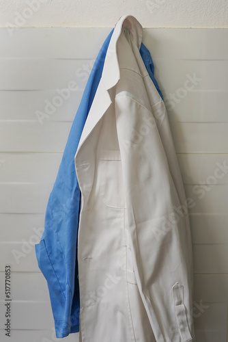 Φωτογραφία White and blue smock on wooden hanger on ceramics wall background