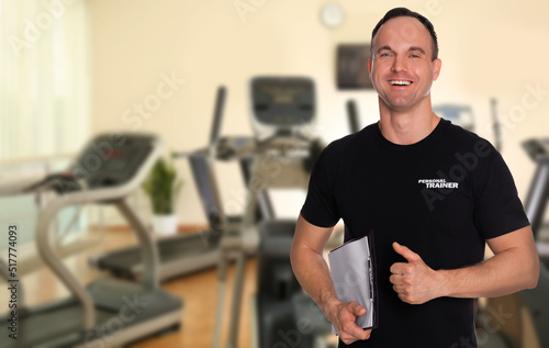 Portrait of professional personal trainer with clipboard in gym. Space for text