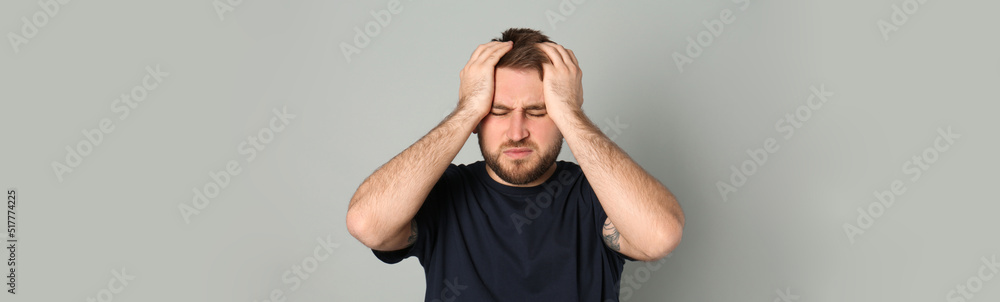 Naklejka premium Tired man suffering from migraine on grey background. Banner design