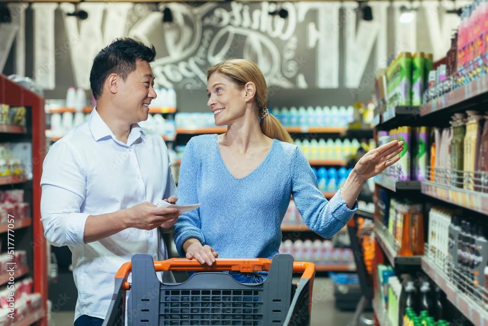 Happy shoppers Asian man and woman buy and choose goods in supermarket, family shopping