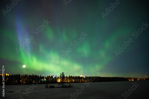 A various colour geomagnetic Aurora borealis on the starry night sky over a city. Aurora Borealis over Swedish lake Islands. Northern Sweden