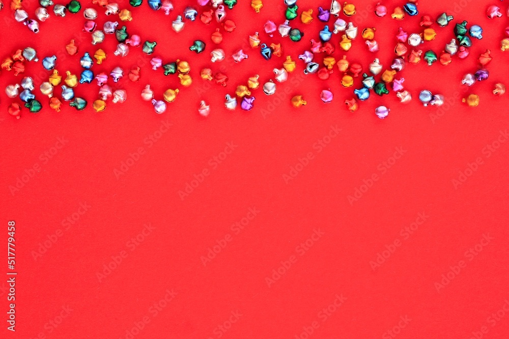 Obraz premium Little christmas colourful jingle bells on red background with copy space for text. Holiday festive happy new year concept. Idea for greeting postcard, poster, banner. Mock up, flatlay, top view