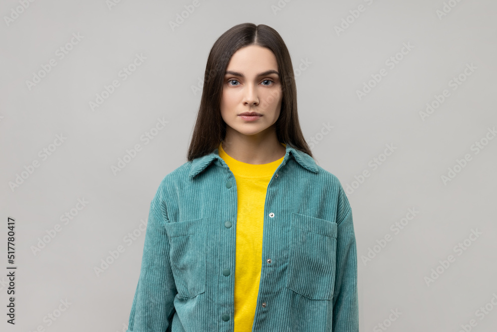 Portrait of strict bossy woman looking at camera, feels confident focused self-assured, expressing seriousness, wearing casual style jacket. Indoor studio shot isolated on gray background. Portrait of strict bossy woman looking at camera, feels confident focused self-assured, expressing seriousness, wearing casual style jacket. Indoor studio shot isolated on gray background.