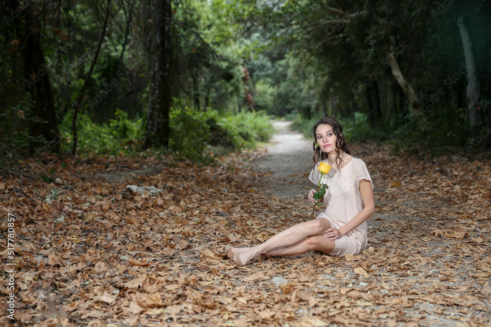 Young Woman Sitting And Holding A Yellow Rose In The Forest Young Woman Sitting And Holding A Yellow Rose In The Forest