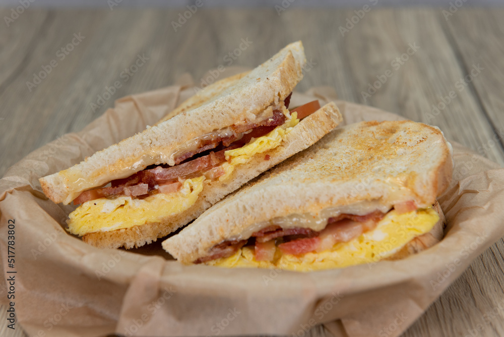 Grilled breakfast sandwich with scrambled eggs, bacon, and cheese on sour dough toast bread