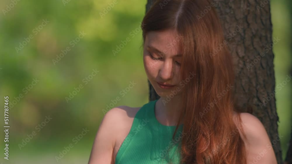 Young redhead girl reading book in green park in the open air in summertime. Development of imagination, education Young redhead girl reading book in green park in the open air in summertime. Development of imagination, education