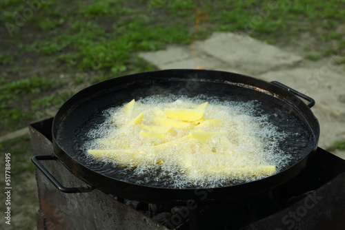 Cooking delicious potato wedges on frying pan outdoors