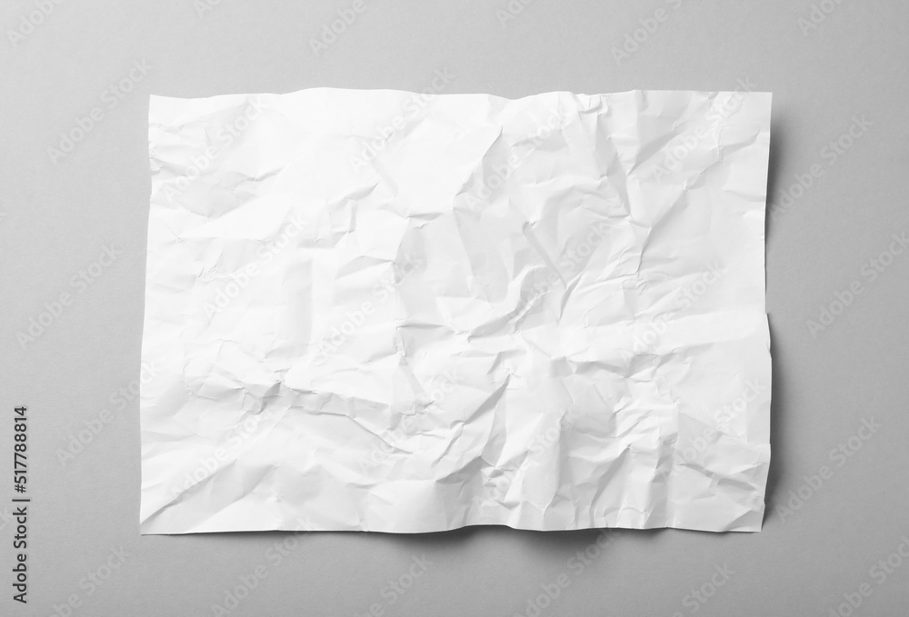Obraz premium Sheet of white crumpled paper on grey background, top view