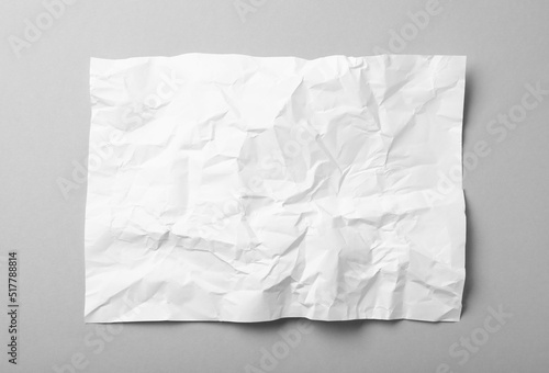 Sheet of white crumpled paper on grey background  top view