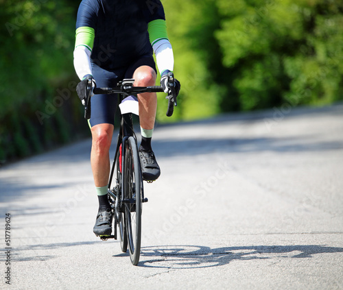 cyclist with racing bike and sportswear while pedaling on the asphalt road outside the city during training
