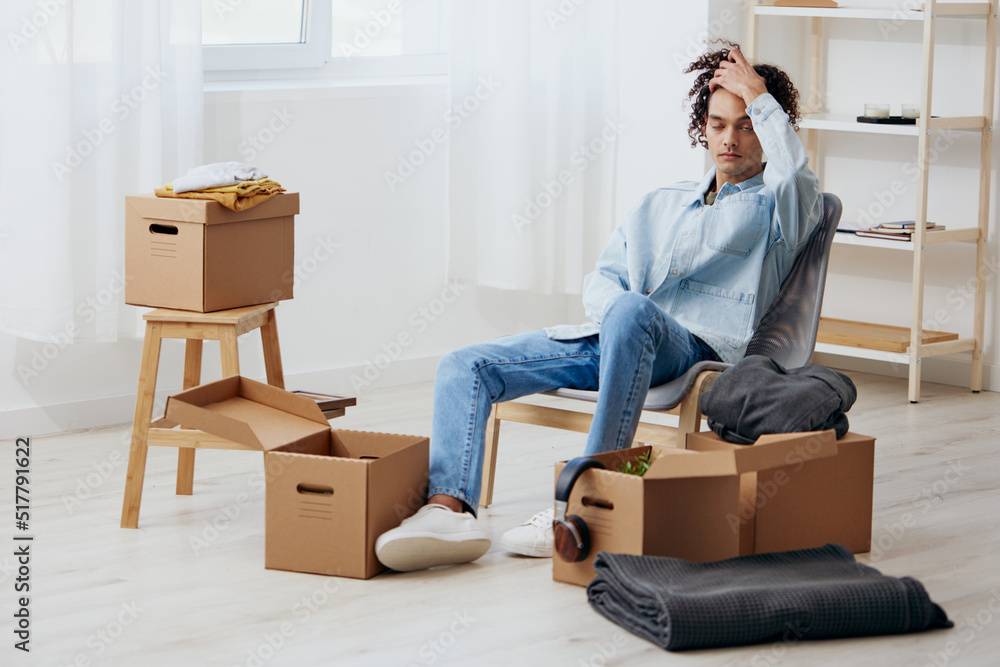 guy with curly hair unpacking things from boxes in the room sorting things out guy with curly hair unpacking things from boxes in the room sorting things out