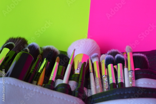 Professional cosmetic makeup brushes of different sizes on a pink and green background for applying powder  shadows and blush and other cosmetic products