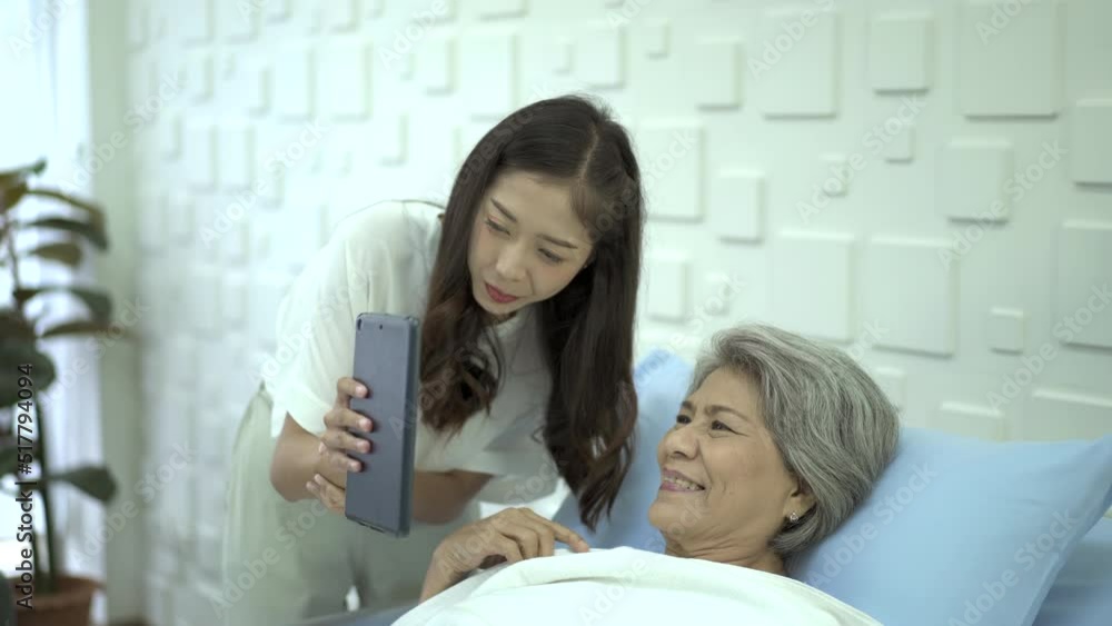 Daughter visiting his mother in hospital and let her talk to family on a video call on digital tablet. Daughter visiting his mother in hospital and let her talk to family on a video call on digital tablet.