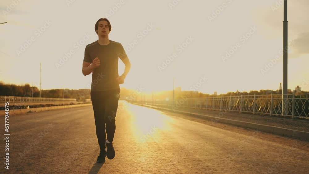 yougn athletic man is jogging alone on empty road in sunny morning in summer, sport activity yougn athletic man is jogging alone on empty road in sunny morning in summer, sport activity