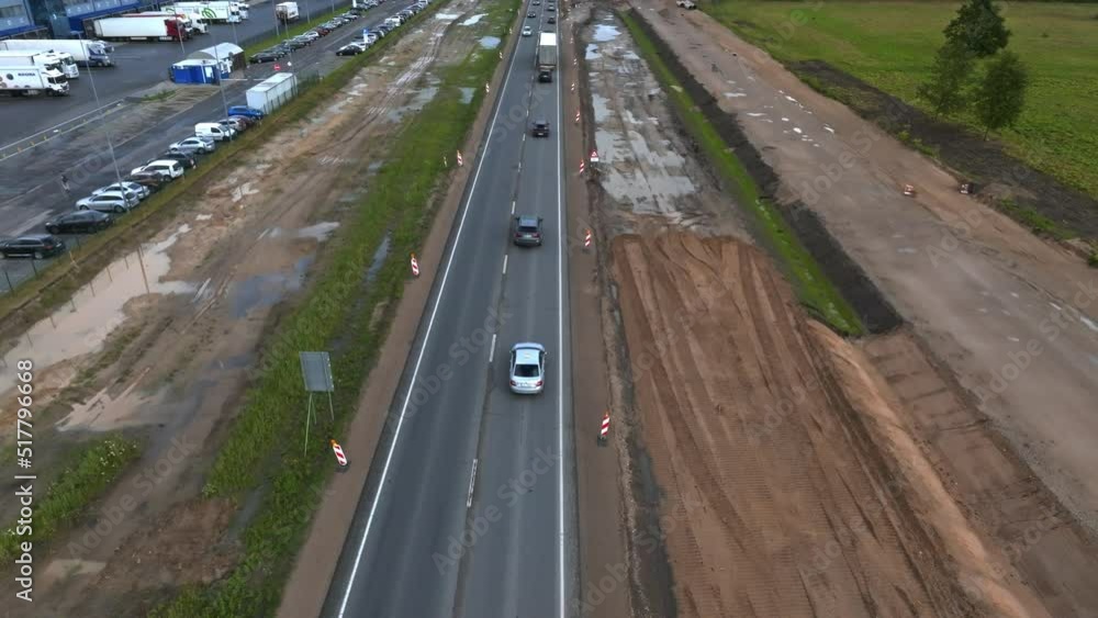 Aerial view of the highway going through the green fields and forests. Traffic moving down the highway in Europe. Aerial view of the highway going through the green fields and forests. Traffic moving down the highway in Europe.