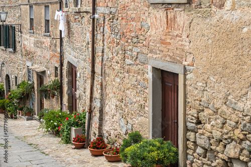 Picturesque ancient light stone buildings with lots of flower pots beside doors and building wall.  © Silga