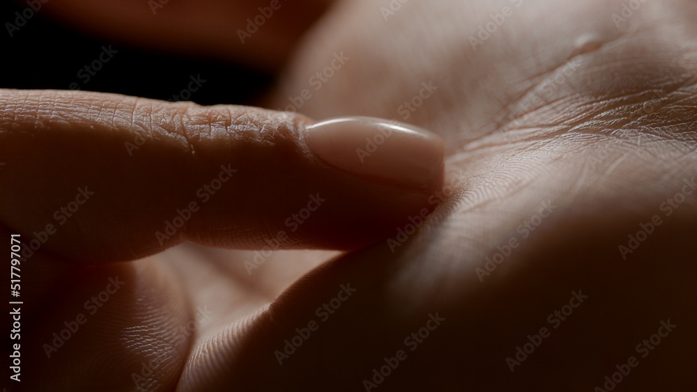 Macro shot of woman's finger touches her soft clean palm on black background | Skin texture shot for skin nutrition concept Macro shot of woman's finger touches her soft clean palm on black background | Skin texture shot for skin nutrition concept