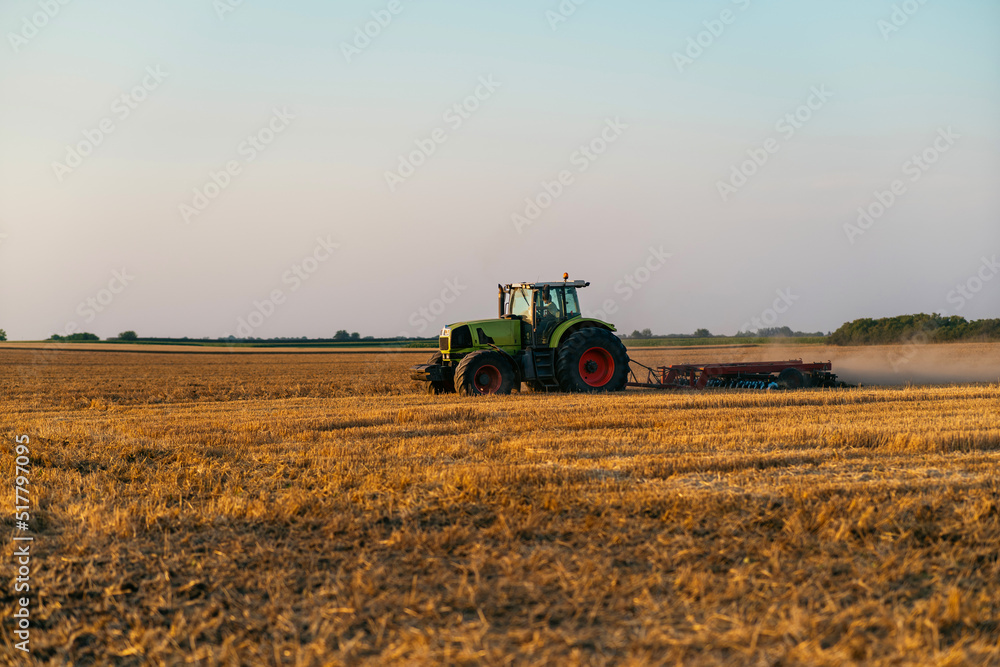 Obraz premium Tractor plowing the field after harvest.