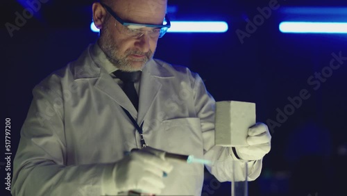 Professional tester testing , burning piece of fireproof building material  by gas torch inside  futuristic laboratory.  Construction engineer doing experiment . Physicist working in lab . Slow motion photo