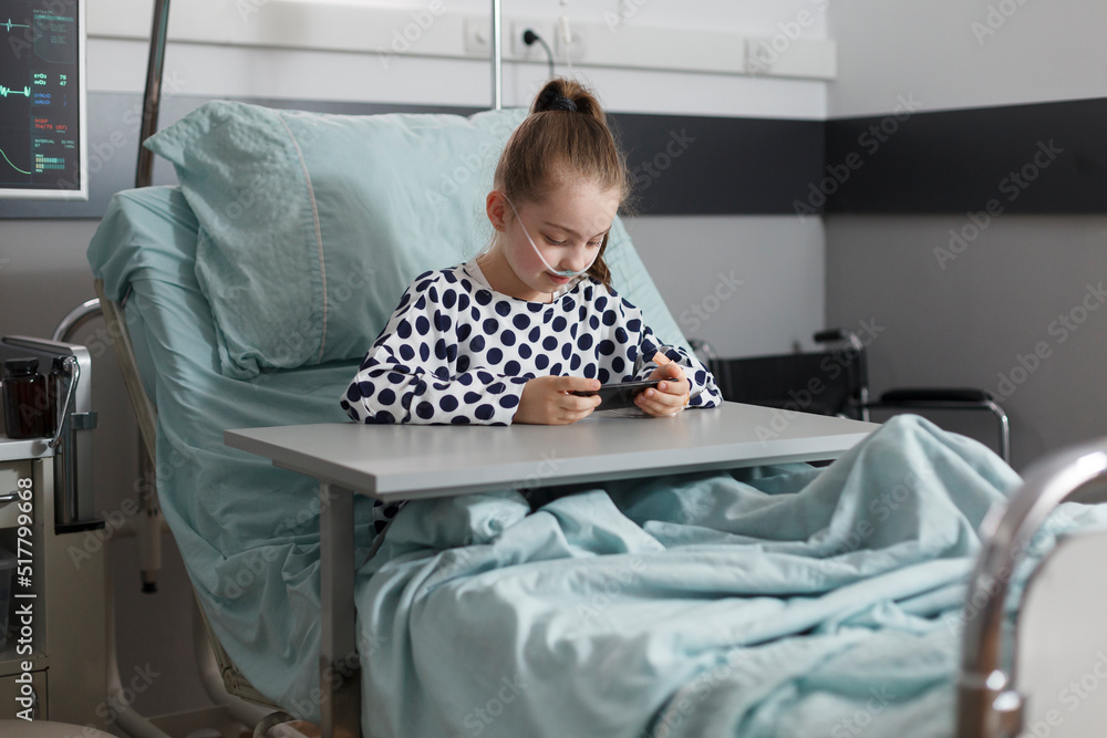Sick girl under treatment resting on patient bed while watching ...