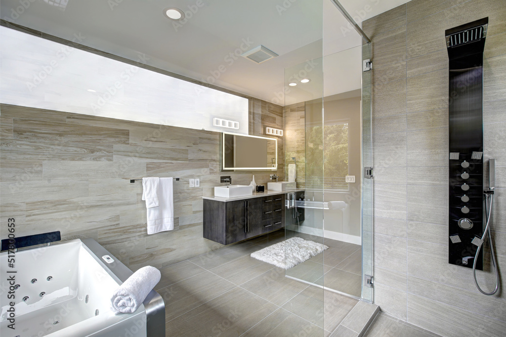 Contemporary luxury bathroom interior with beige ceramic tiles and hot tub without shower curtain. Standing in the shower with large glass door. Contemporary luxury bathroom interior with beige ceramic tiles and hot tub without shower curtain. Standing in the shower with large glass door.