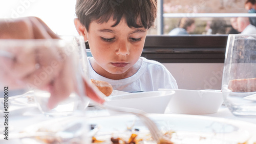 elementary age kid sadly looking food plate in a restaurant.  eating disorder in childhood concept. children depression photo