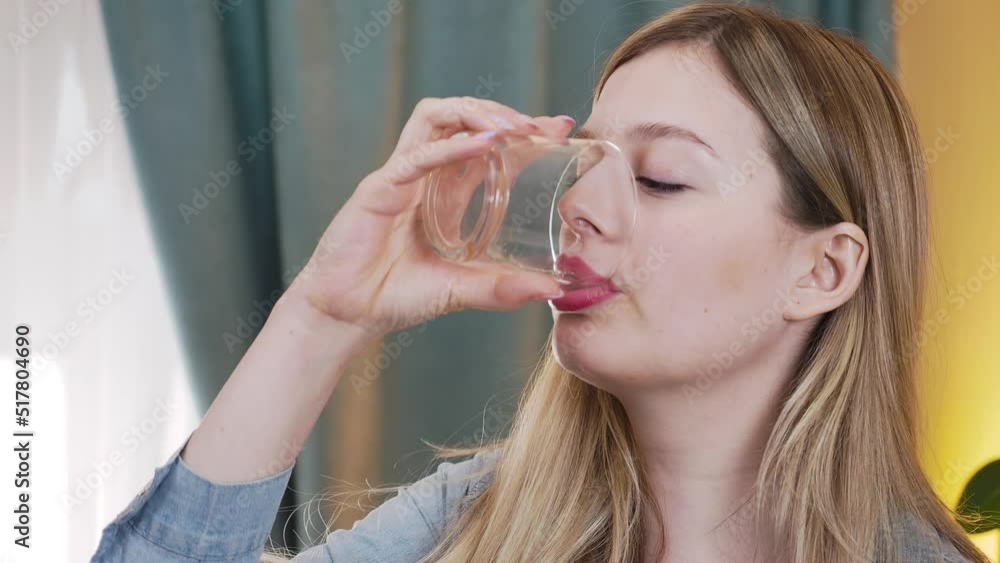 A young beautiful woman takes a pill and drinks water from a glass A young beautiful woman takes a pill and drinks water from a glass