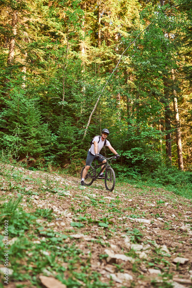 Naklejka premium A cyclist rides a bike on extreme and dangerous forest roads. Selective focus