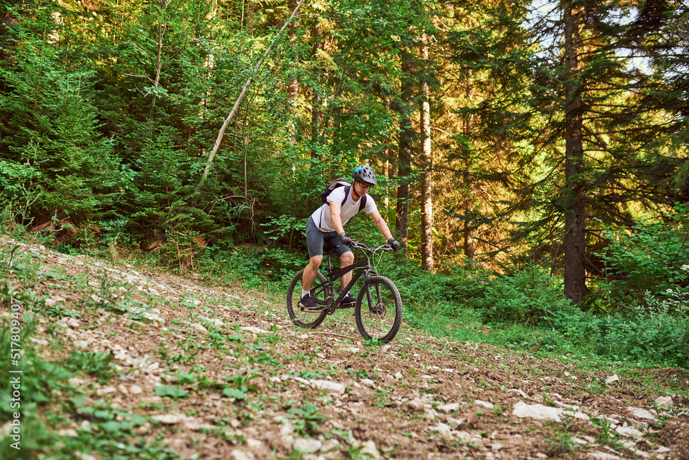 Naklejka premium A cyclist rides a bike on extreme and dangerous forest roads. Selective focus