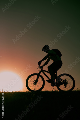 A cyclist riding a bike on a mountain at sunset