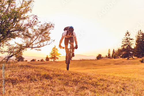 Tableau sur toile A cyclist rides a bike on forest roads at sunset