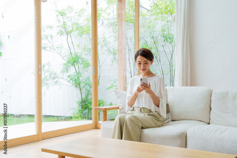 リビングでスマートフォンを使う女性 リビングでスマートフォンを使う女性