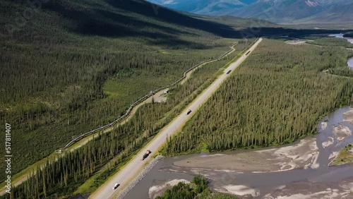 Aerial tilt up on Alaska Brooks Range Mountain Portage Valley with Tank Trucks driving Portage Glacier road and Trans Alaska crude oil Pipeline  photo