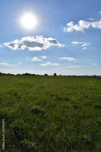 Sun in a Partly Cloudy Sky Over a Rural Farm Field