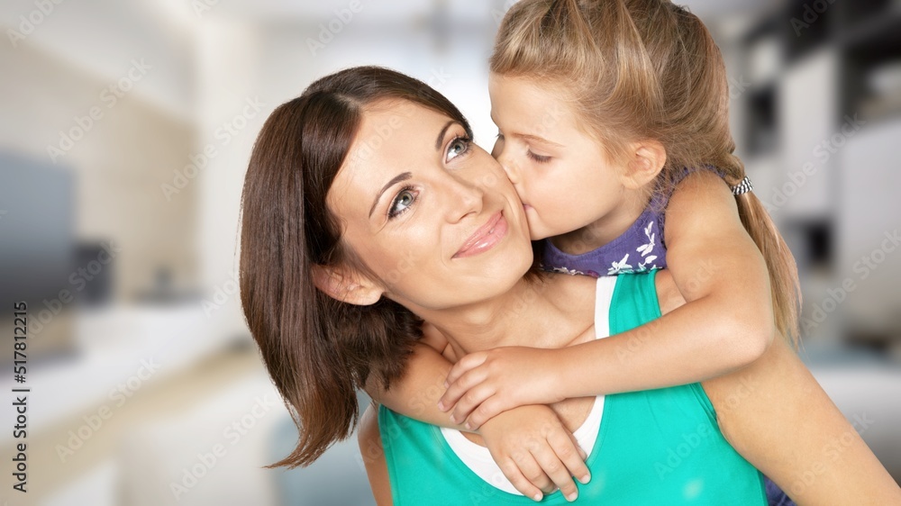 Mother and her little child happily smile and hug in apartment. Happy family.