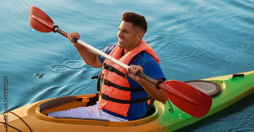 Young man kayaking in river...