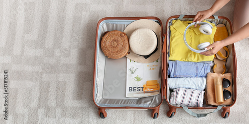Fotografi Woman packing suitcase at home, top view. Travel concept