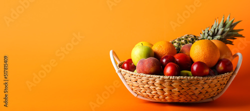 Fototapeta Naklejka Na Ścianę i Meble -  Basket with fresh fruits on orange background with space for text