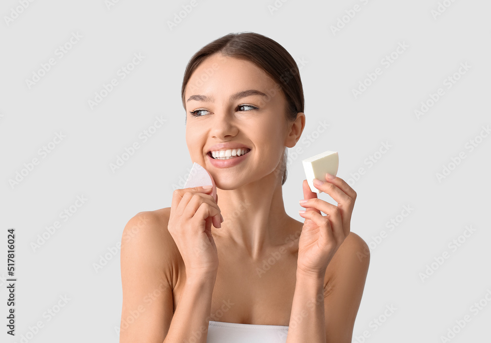 Pretty young woman with makeup sponges on grey background Pretty young woman with makeup sponges on grey background