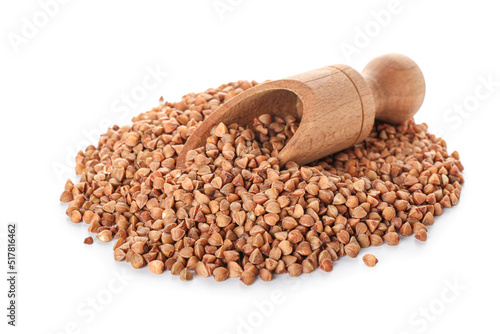 Wooden scoop on heap of buckwheat grains against white background