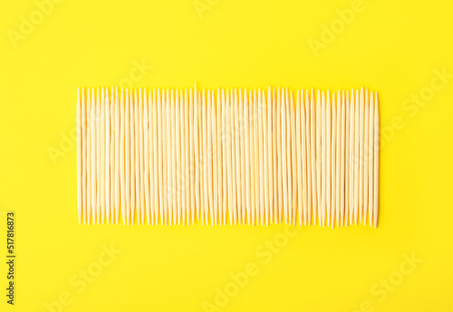 Row of wooden toothpicks on yellow background