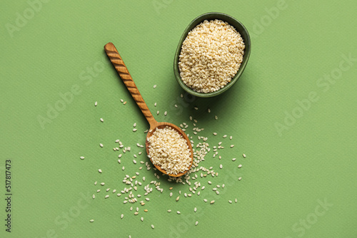 Obraz na plátně Bowl and wooden spoon with sesame seeds on green background