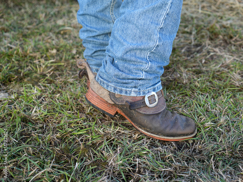 Cowboy boots with spurs worn by male in blue jeans