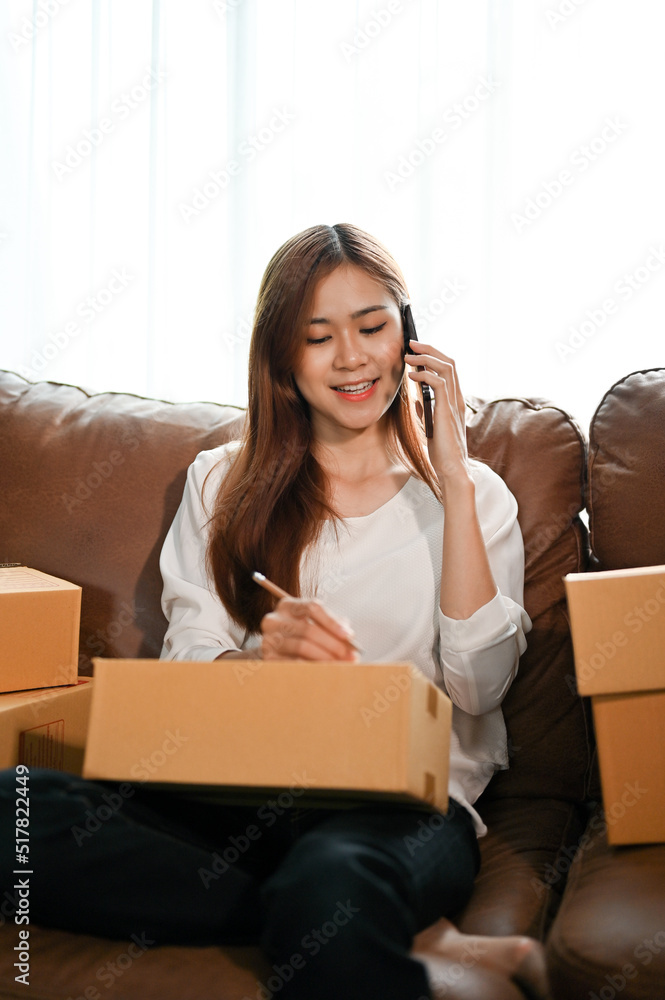 Female preparing customer's package while on the phone with the delivery service Female preparing customer's package while on the phone with the delivery service