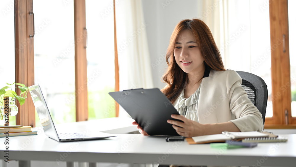 Fototapeta premium Attractive asian businesswoman reading a business report in her private office.